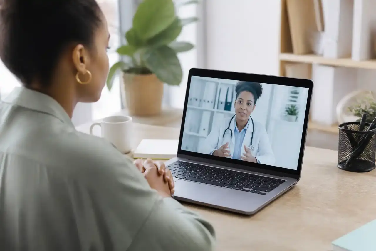 Équipe médicale souriante dans une clinique moderne et lumineuse, discutant autour d'une tablette tactile